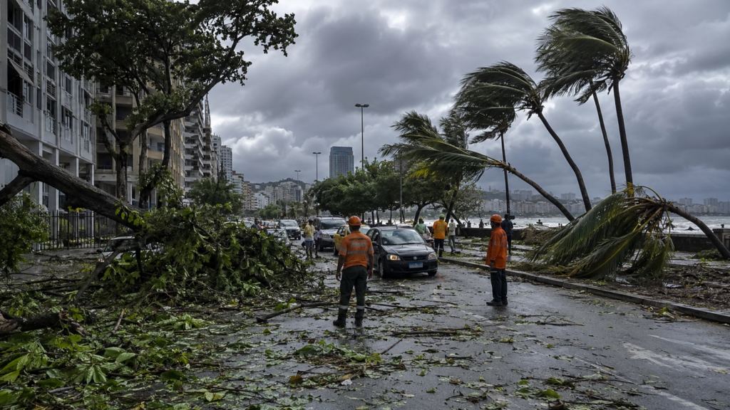 Workers clearing fallen trees on a Rio de Janeiro seafront after a windstorm