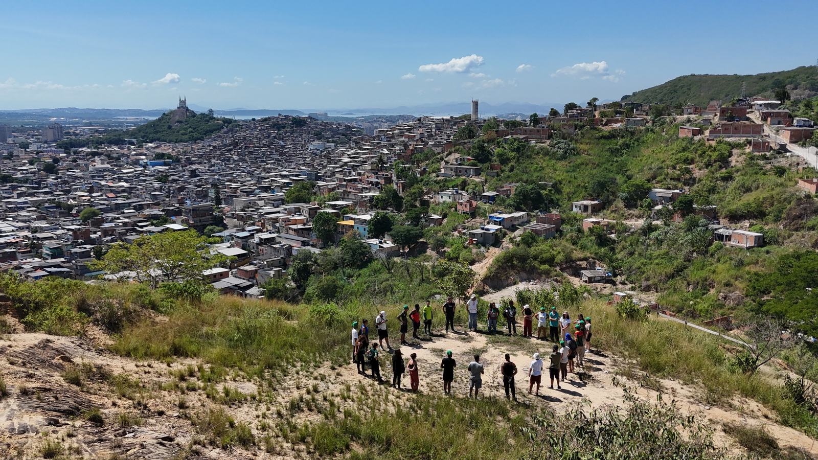 Aerial view of a group gathered on a hillside above a favela